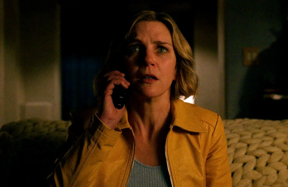 صحنهای از سریال Pluribus که زنی با چهرهای مضطرب و لباس زرد در حال مکالمه تلفنی در یک فضای تاریک است